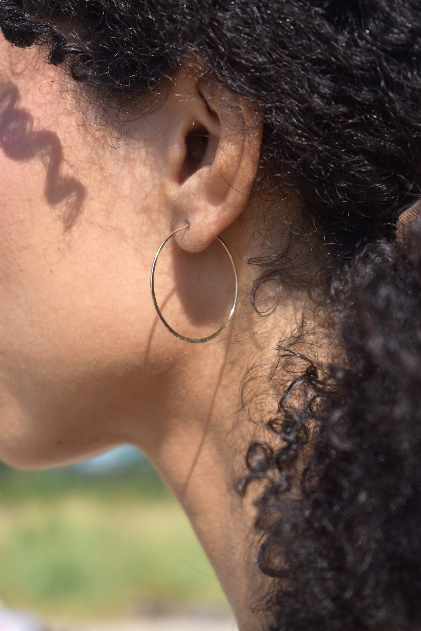 Thin handmade hammered gold hoop on model