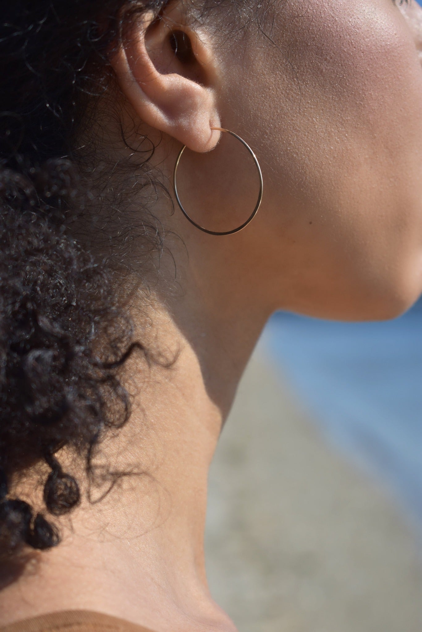 Thin handmade hammered gold hoop on model
