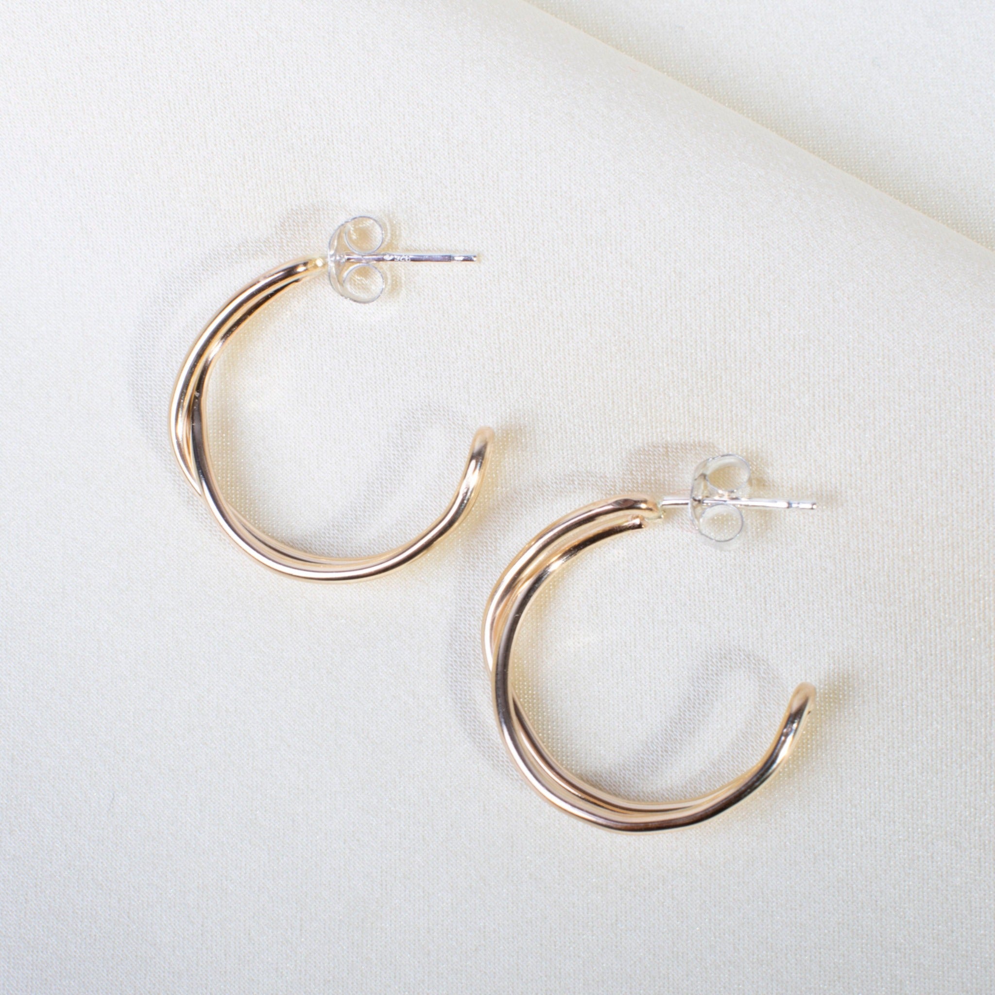 small 14k gold fill cross over hoop earrings on white fabric background