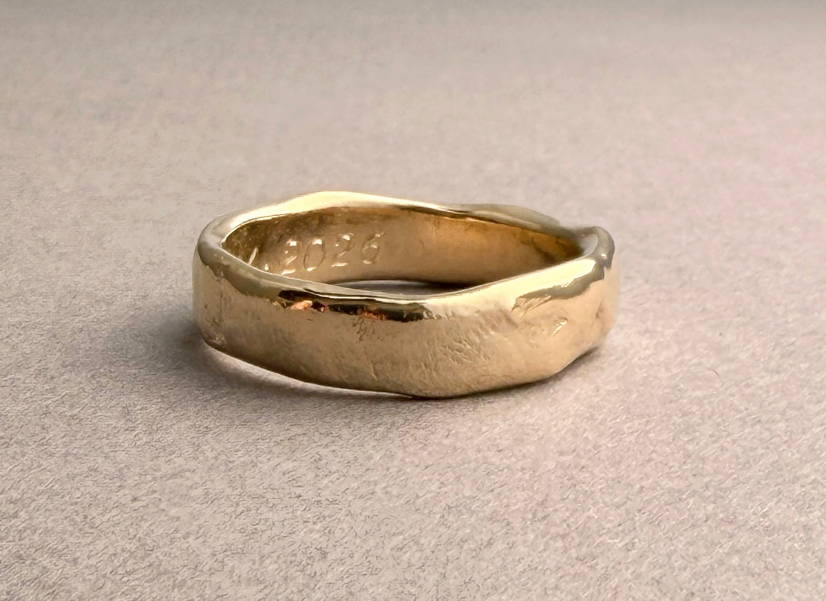 Hand-carved yellow gold wedding band with softly irregular edges and an organic surface