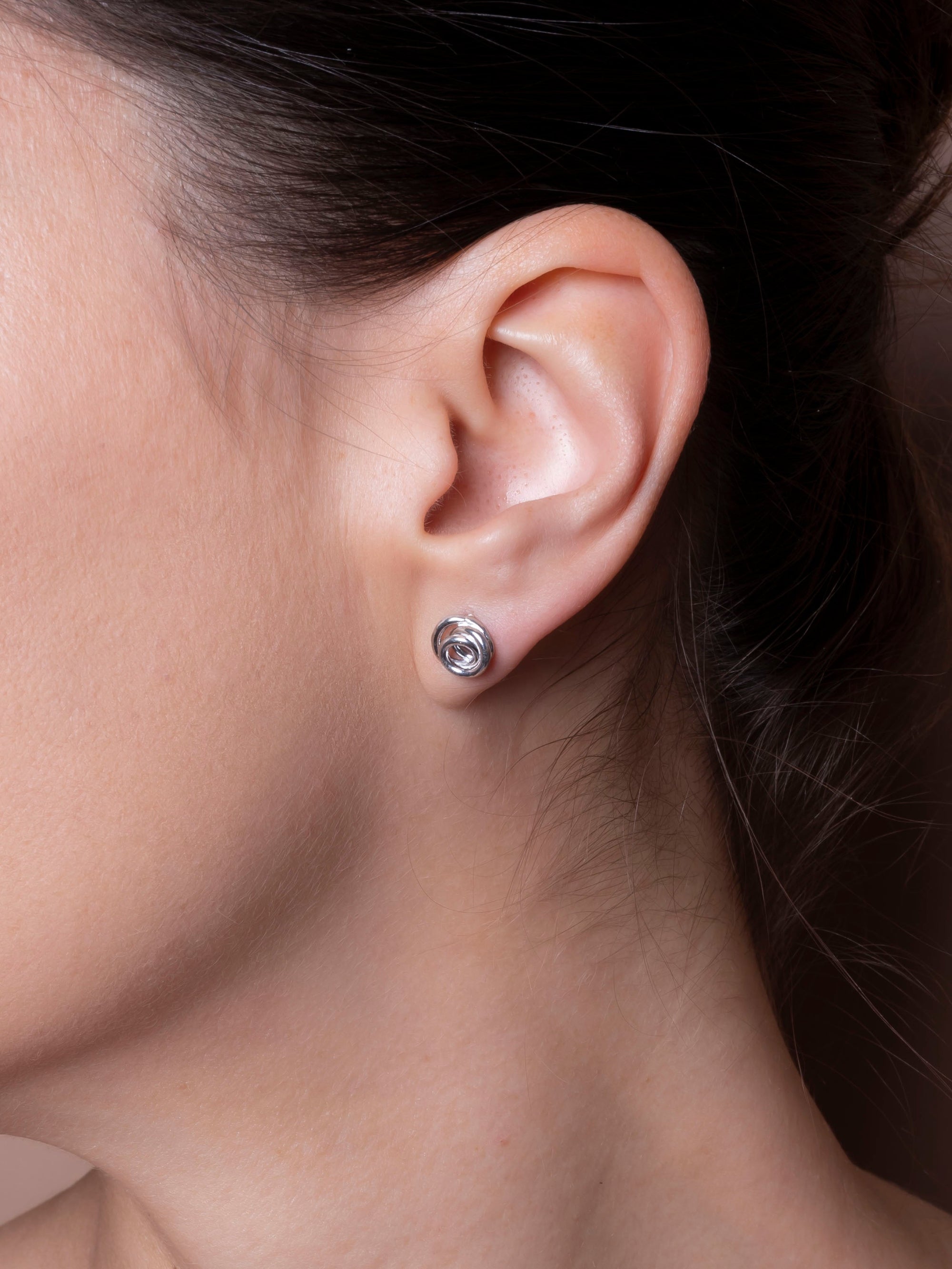 Close-up of an ear wearing a silver earring 