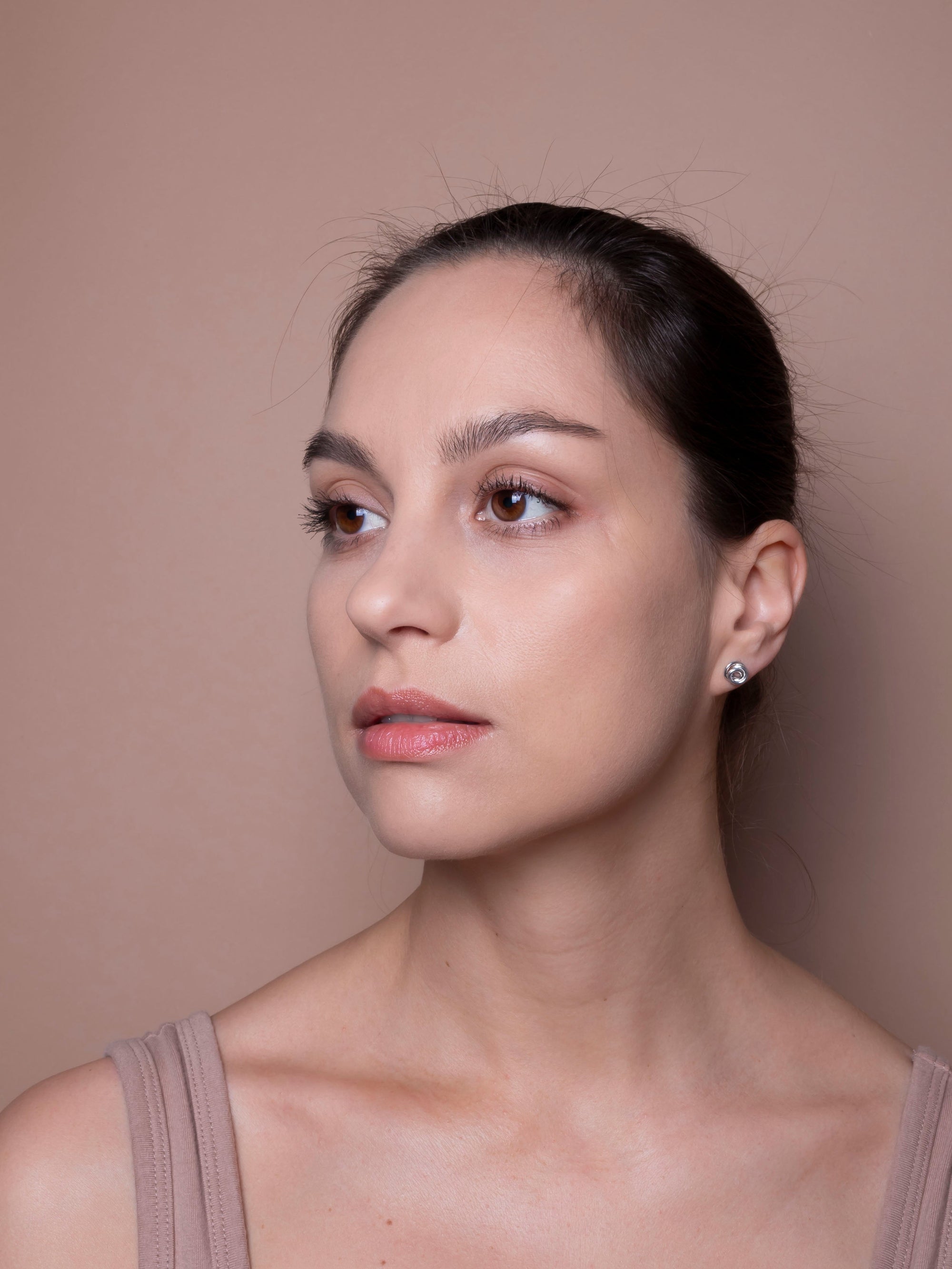 Woman with a neutral expression against a beige background