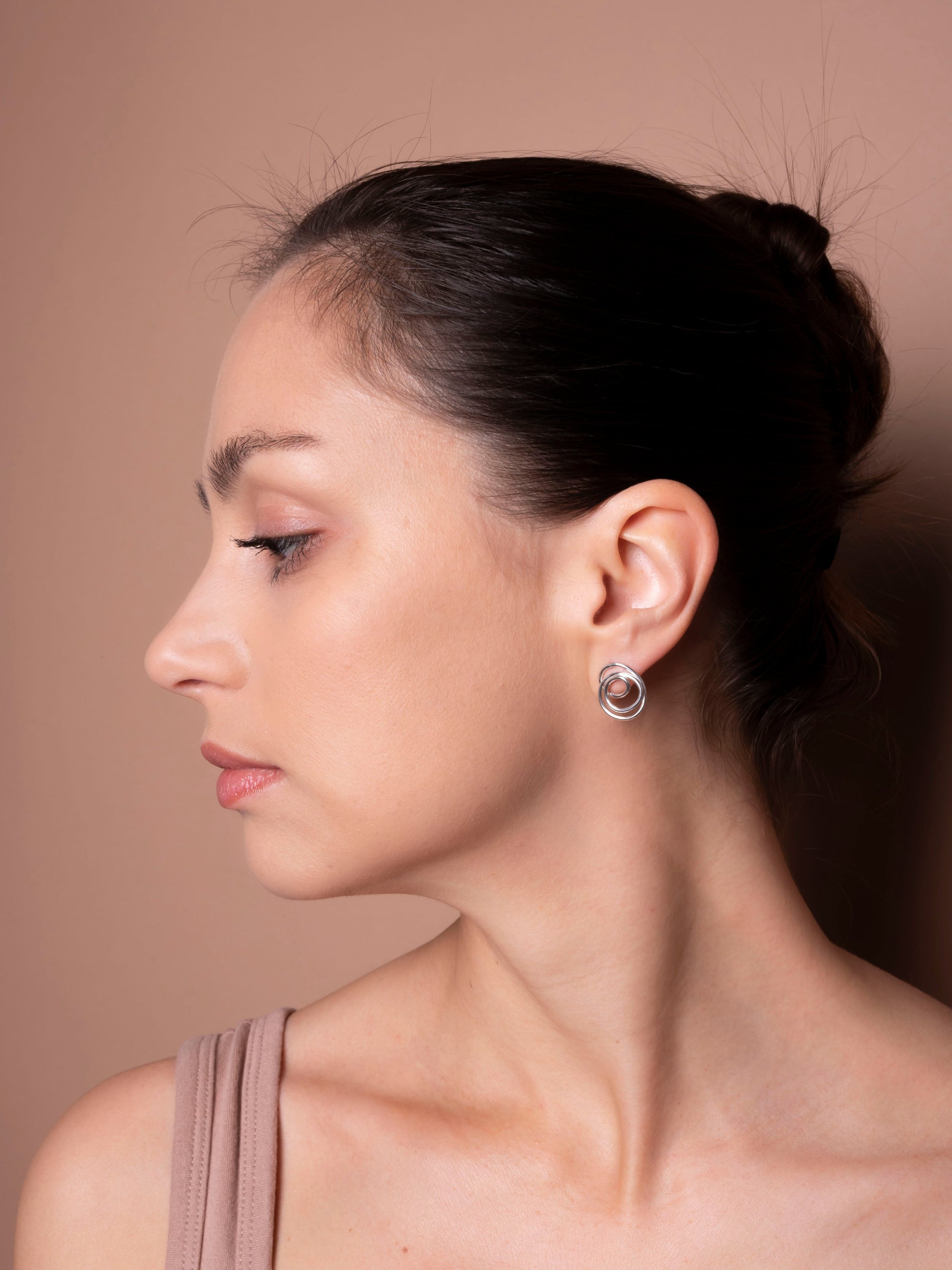 Woman wearing a silver earring against a neutral background