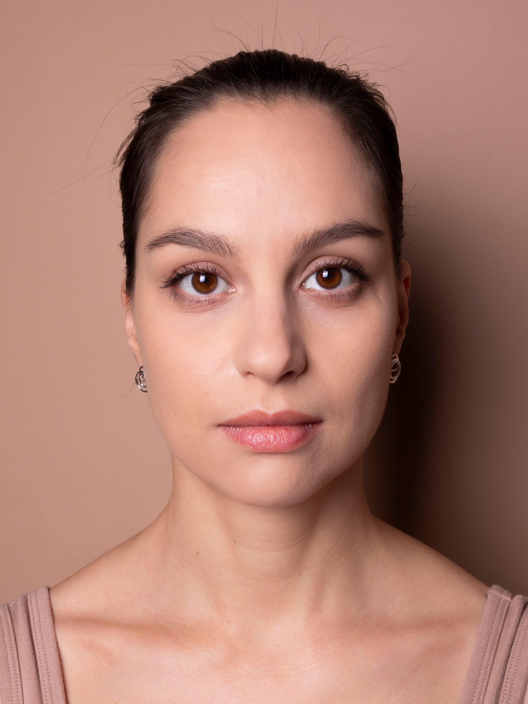 Woman with a neutral expression against a beige background