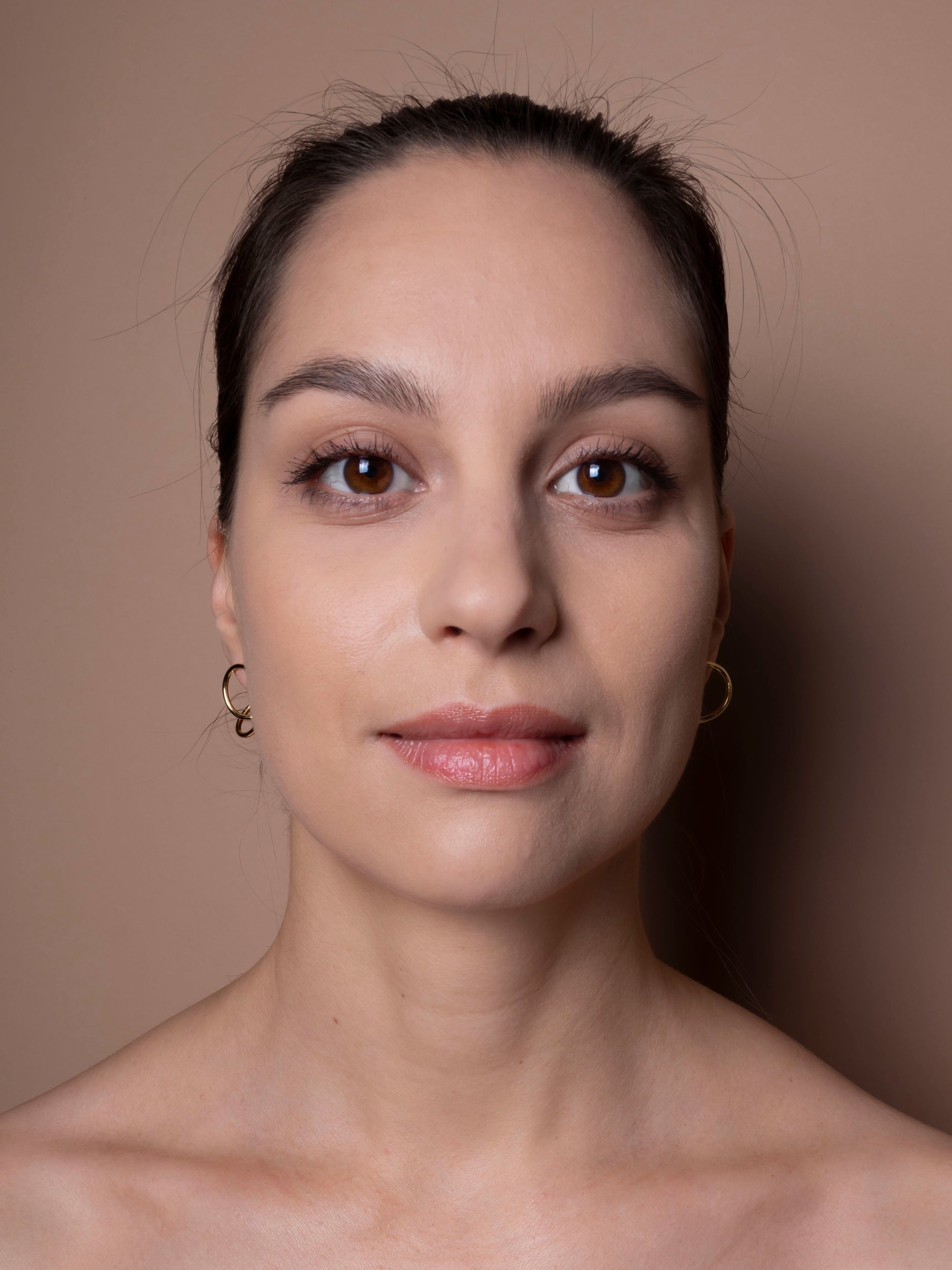 Close-up of a woman with a neutral expression against a plain background