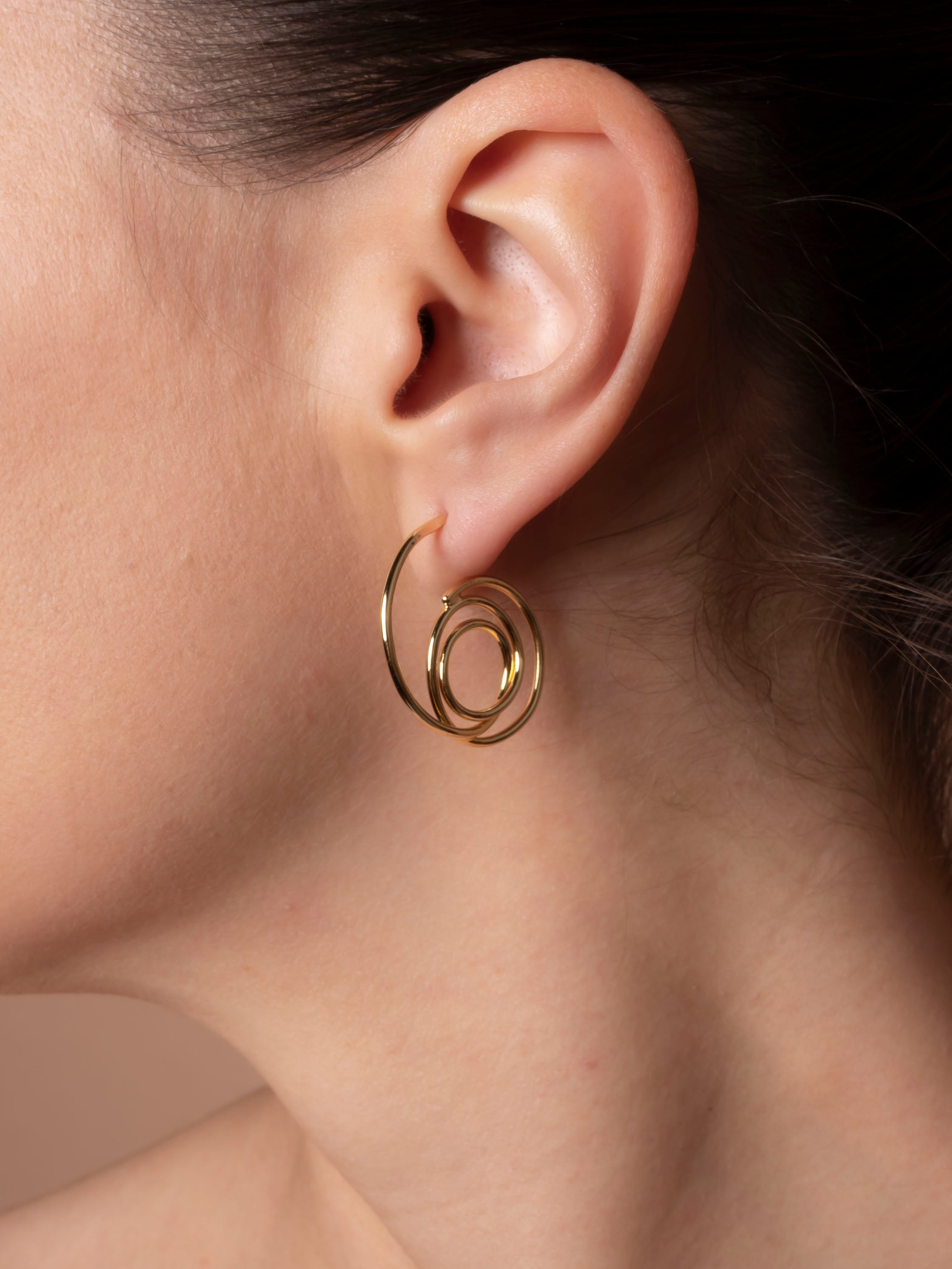 Gold spiral earring on an ear