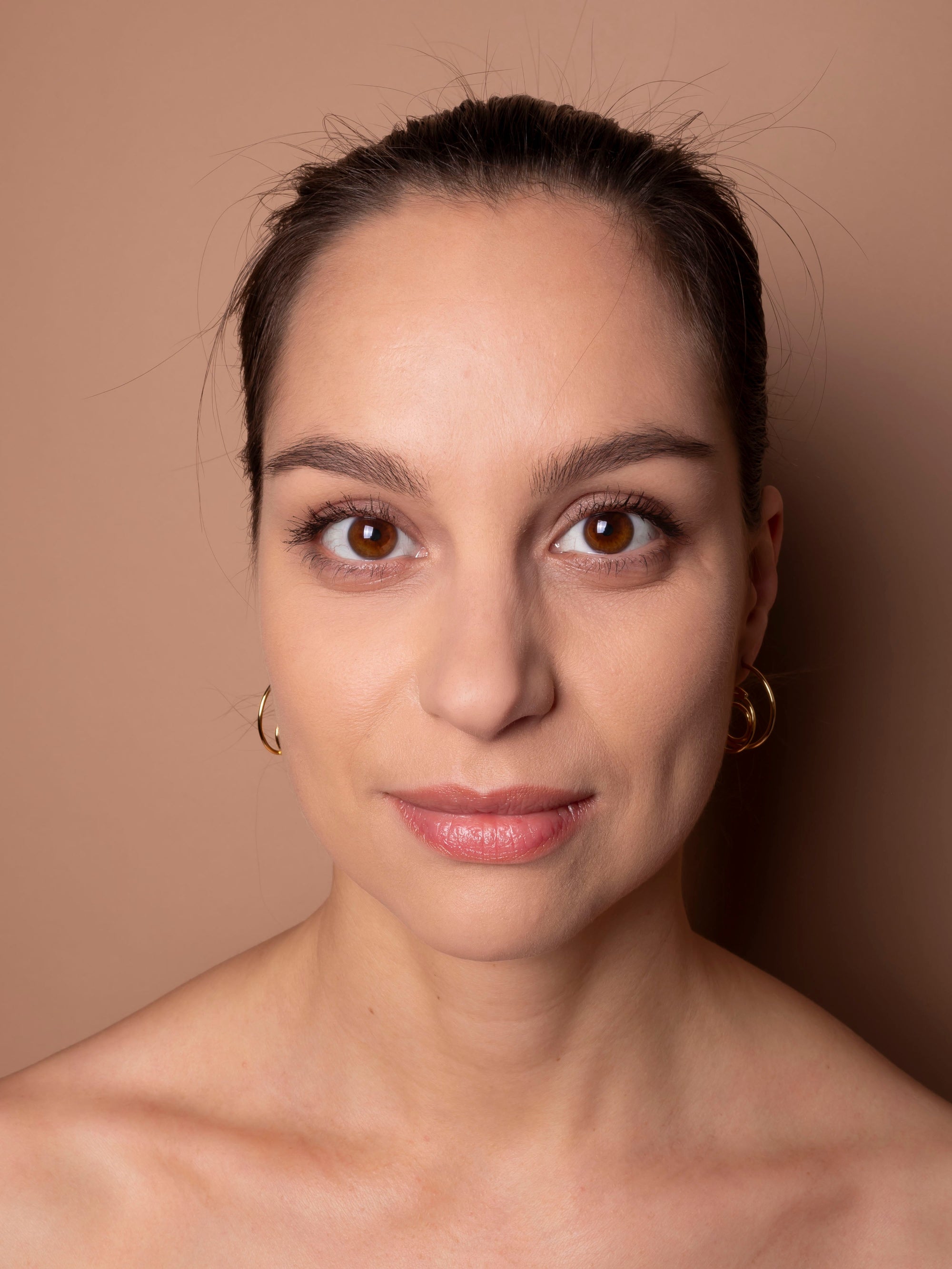 Woman with a neutral expression against a beige background