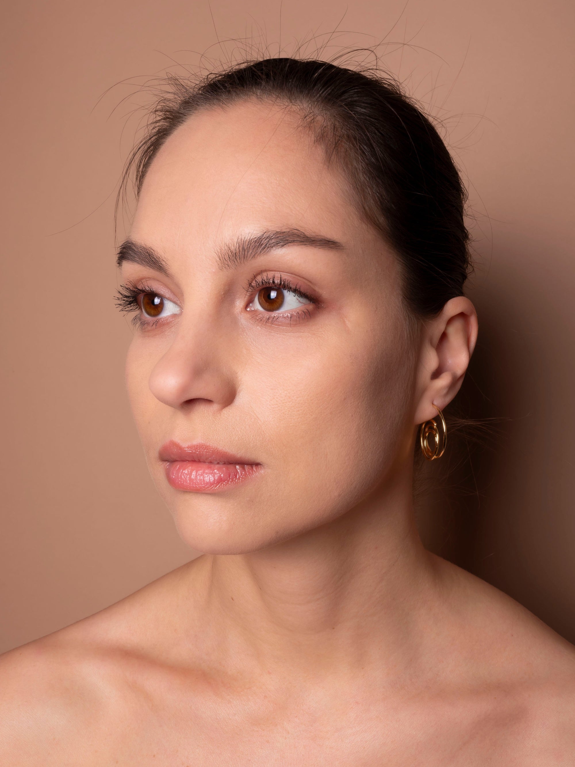 Close-up of a woman with a neutral expression against a beige background