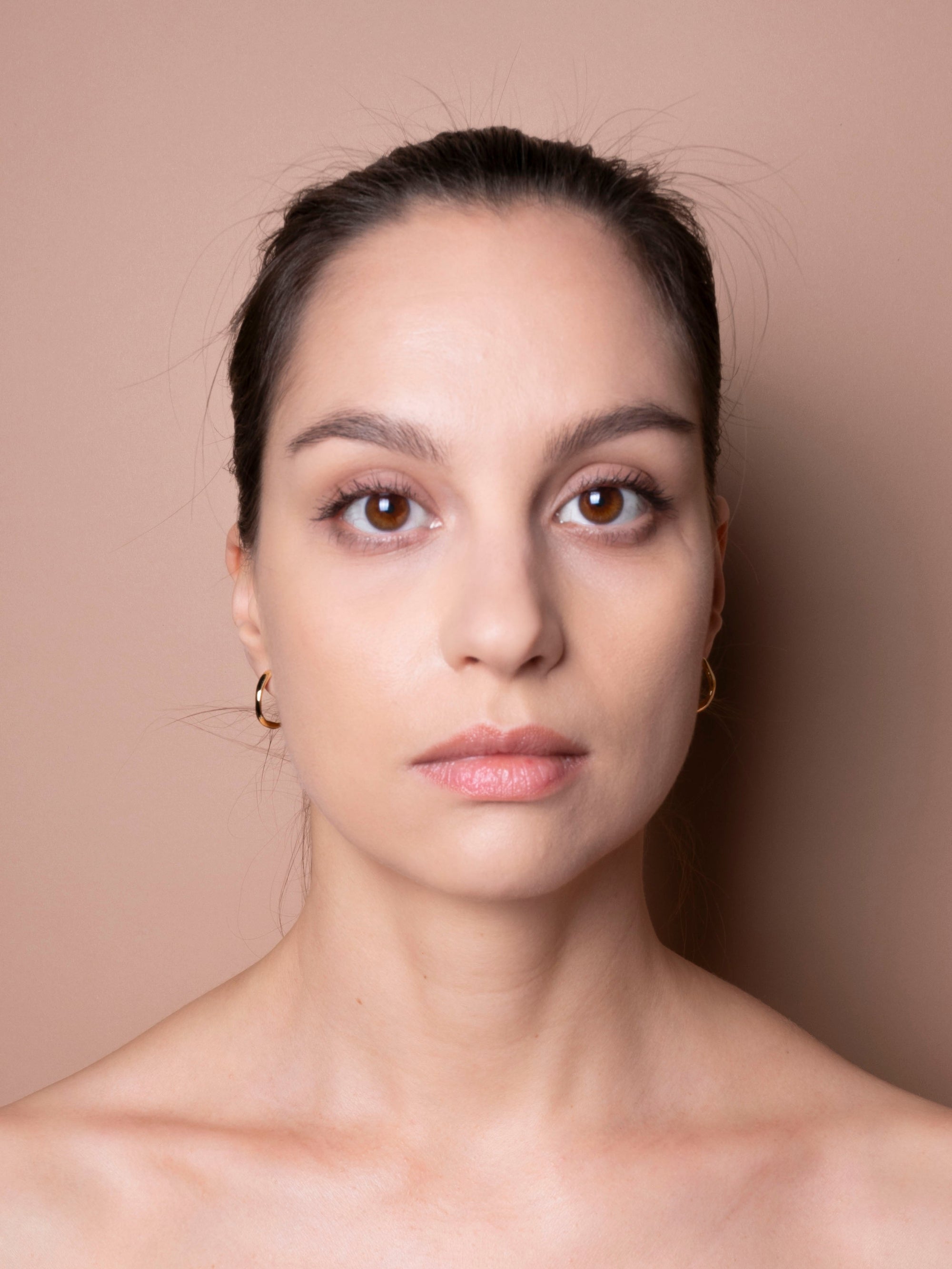 Woman with a neutral expression against a beige background