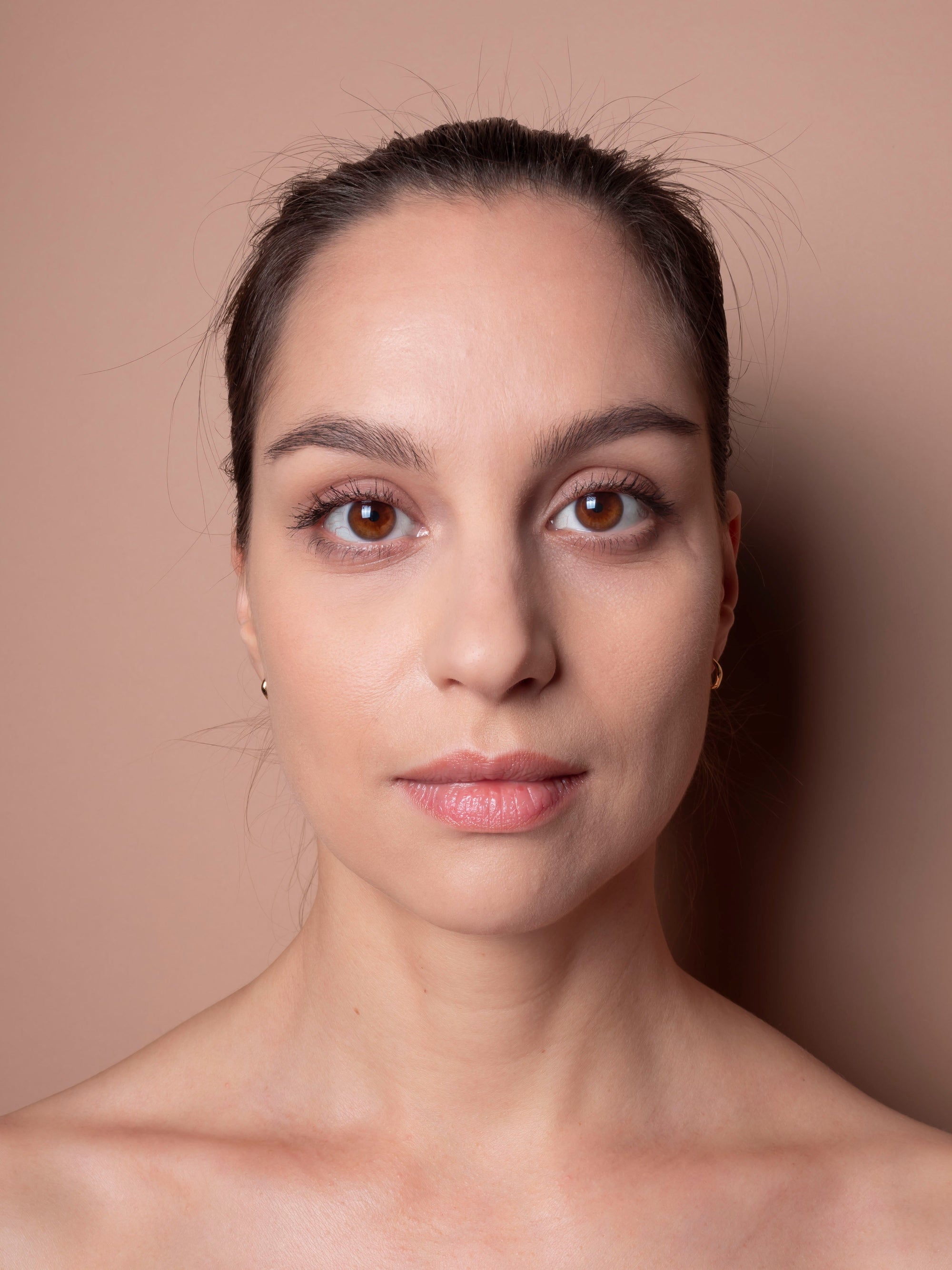 Close-up portrait of a woman with a neutral expression on a beige background
