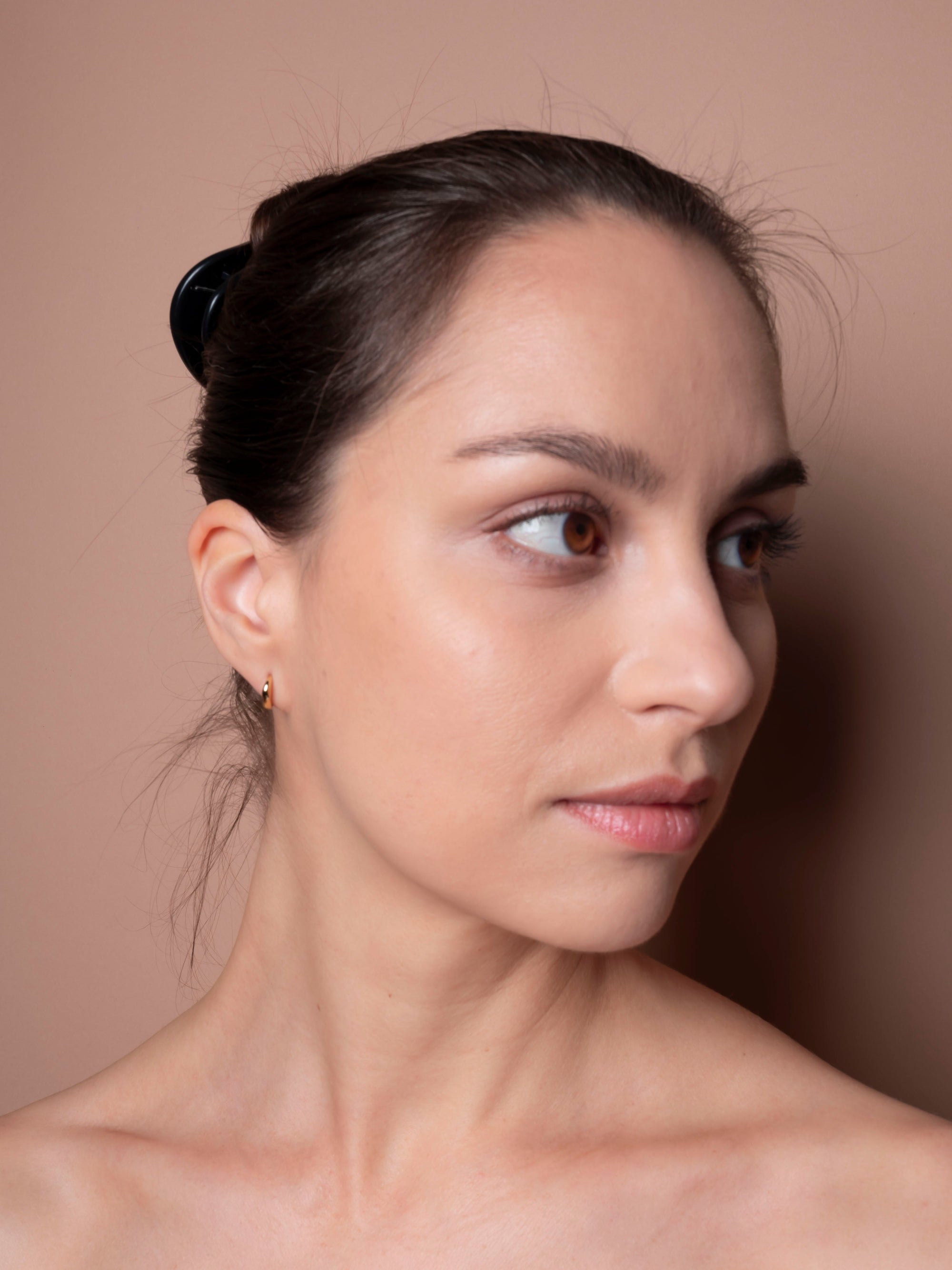 Woman with a neutral expression against a beige background