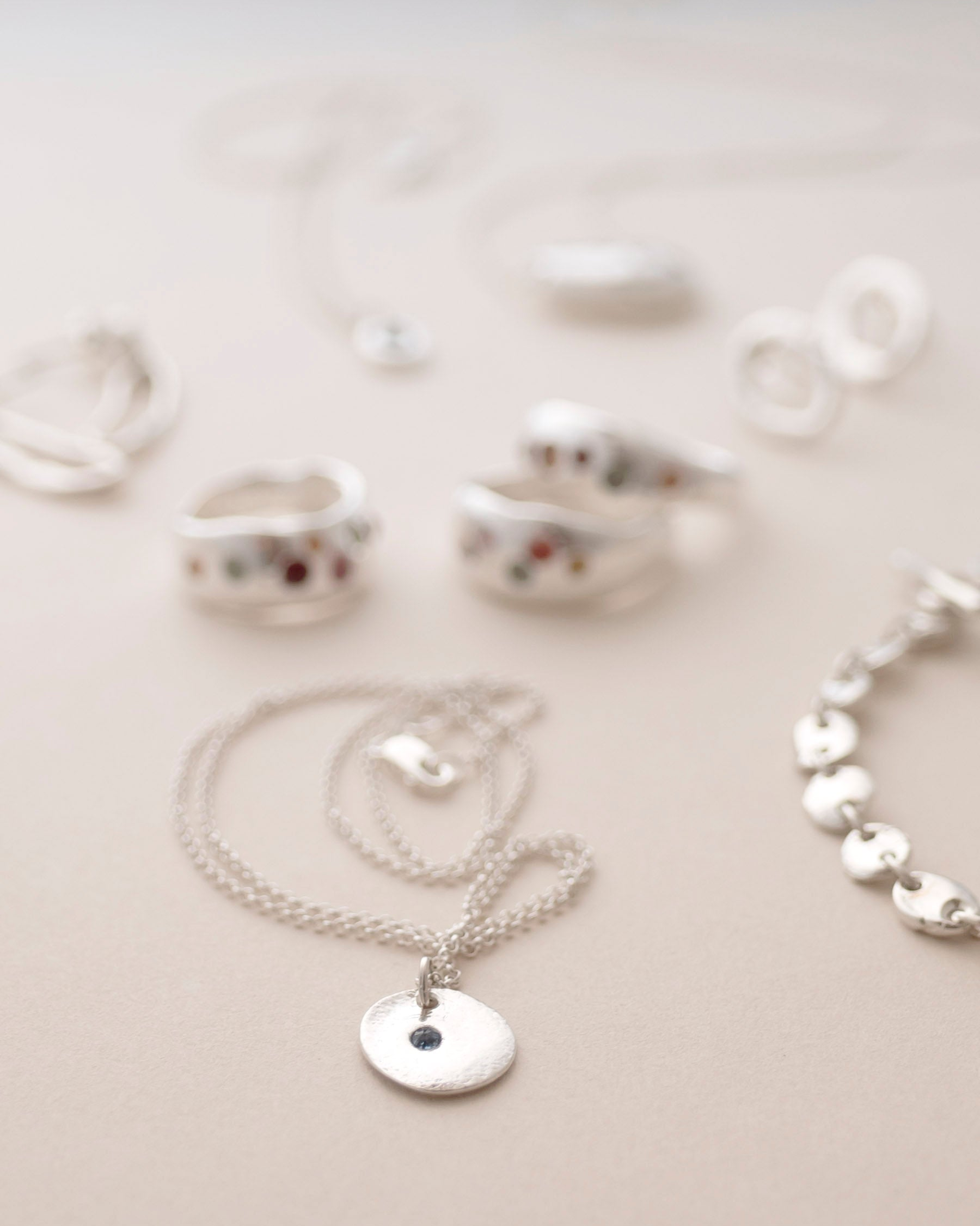 Silver jewelry including a necklace and earrings on a light background