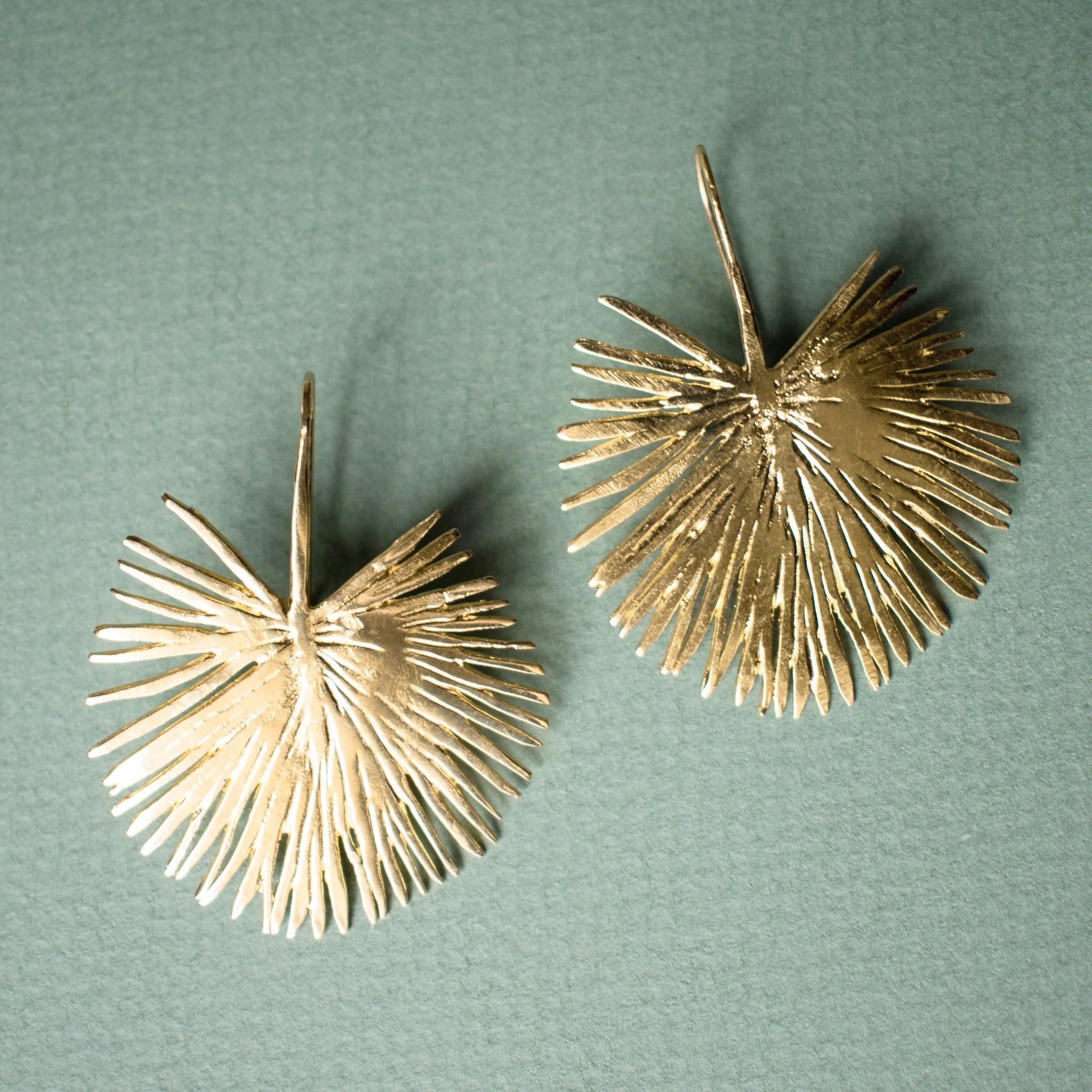 Gold Palm hook earrings on green background