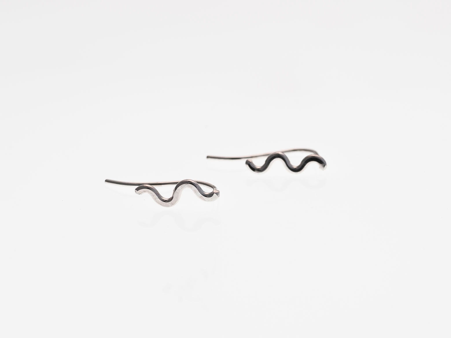 Pair of silver snake-shaped earrings on a white background
