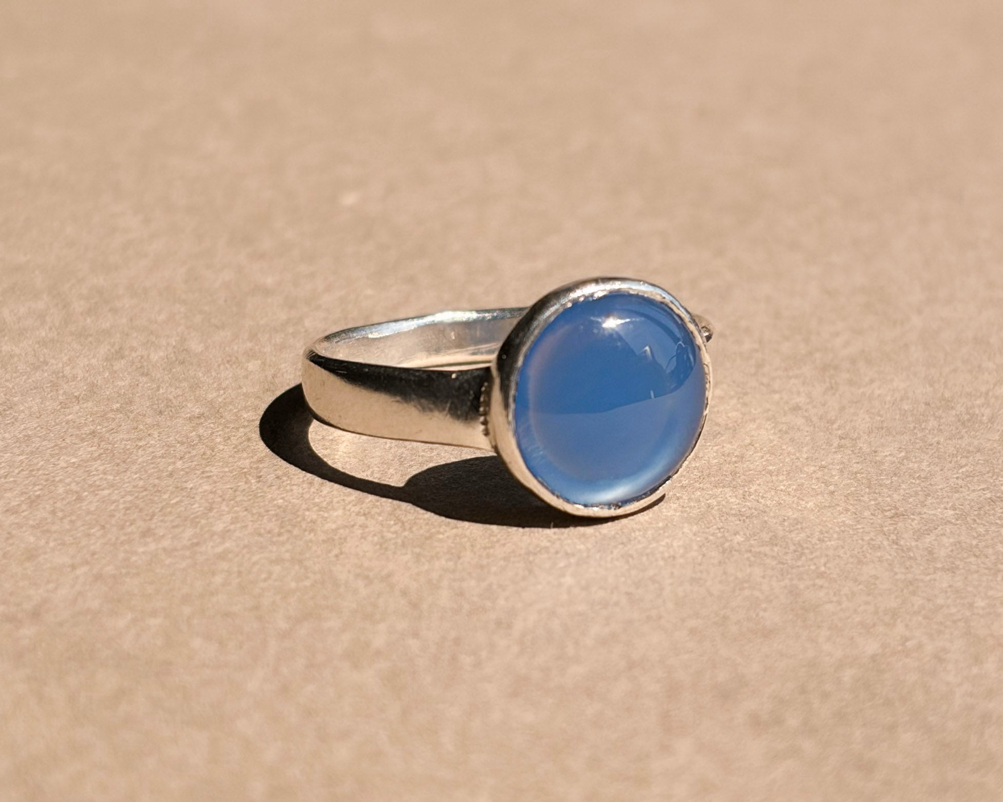 Dyed blue agate set in a sterling silver ring on brown paper
