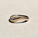 Curved sculptural 14k yellow gold wedding band on pale grey paper