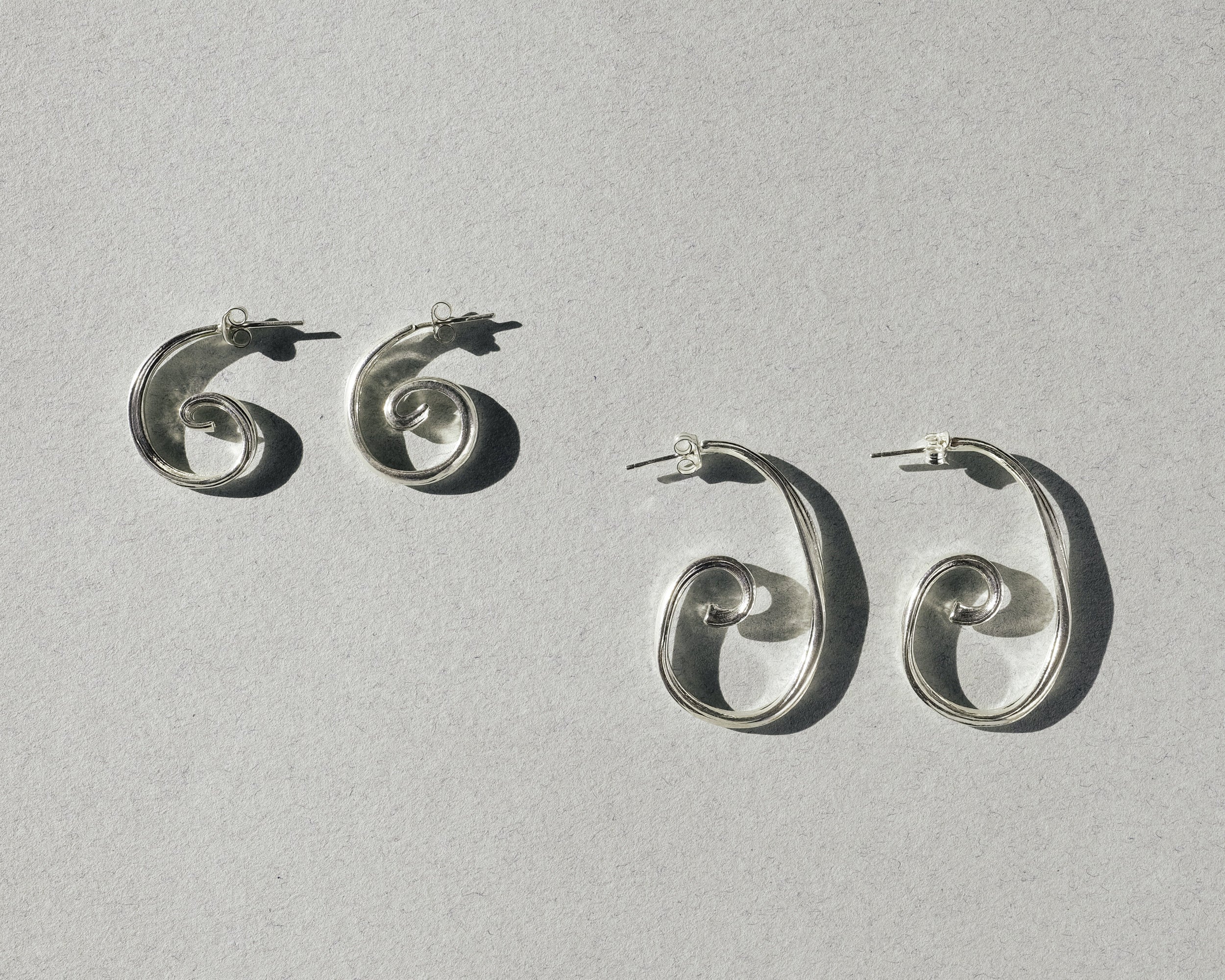 Small and large sterling silver spiral earrings shown side by side for size comparison
