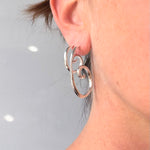 Close-up of a person wearing sterling silver handmade Large and small spiral earring  RA HA Jewelry