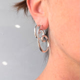 Close-up of a person wearing sterling silver handmade Large and small spiral earring  RA HA Jewelry