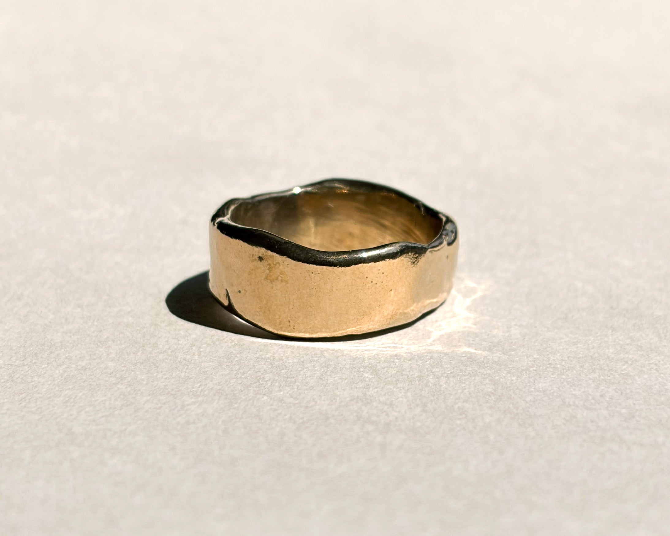 Thick sculptural 14k yellow gold wedding band with organic edges, front view