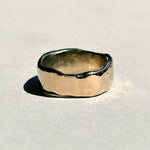 Thick sculptural 14k yellow gold wedding band with organic edges, angled view