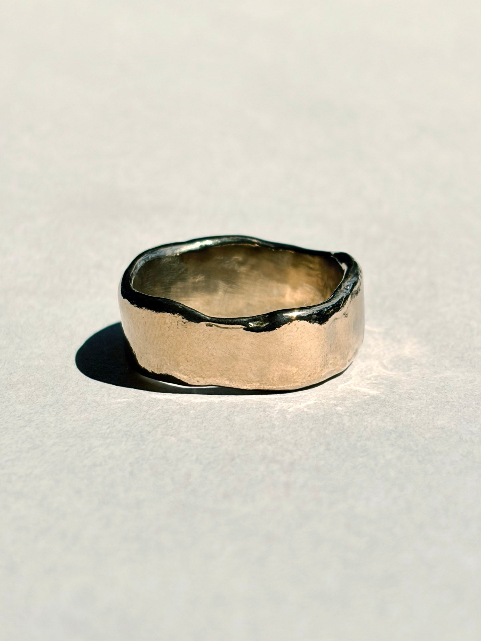 Thick sculptural 14k yellow gold wedding band with organic edges, angled view