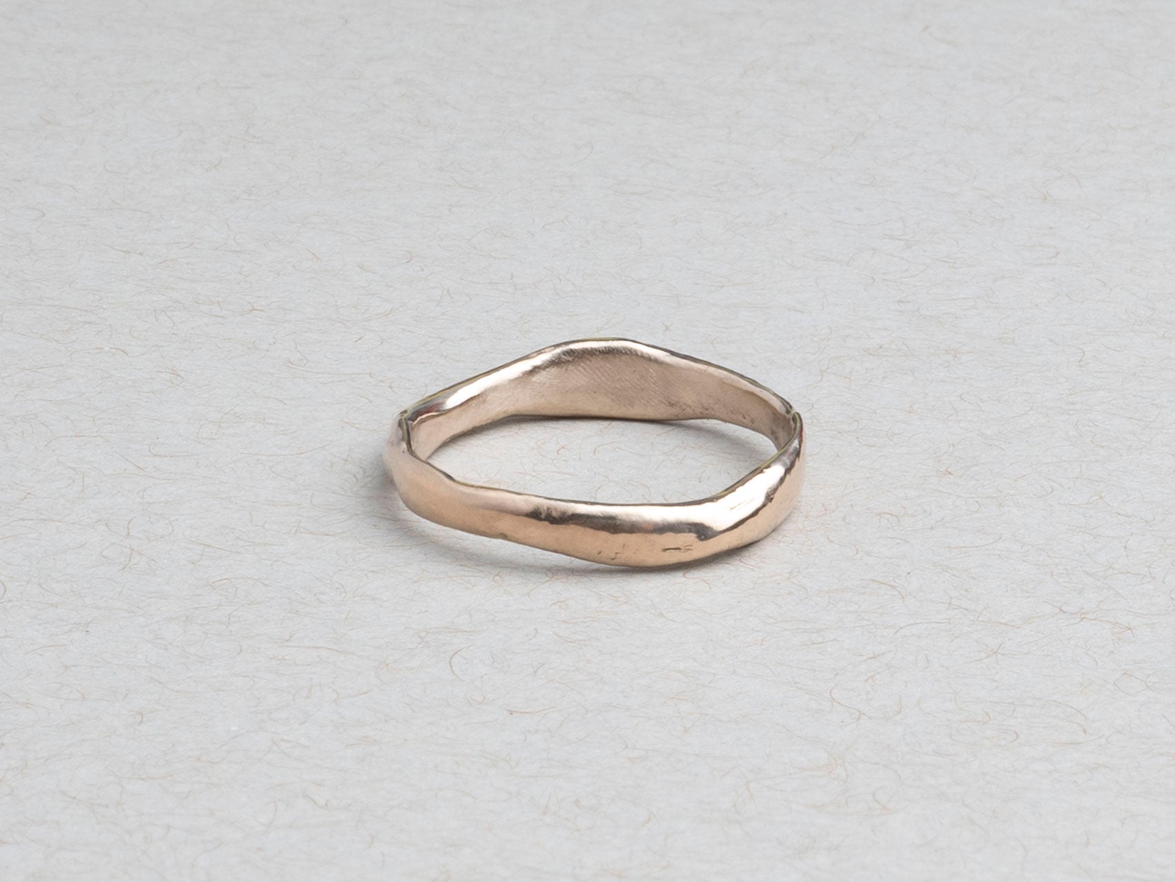 Thin hand-carved 14k gold wedding band with subtle irregular texture