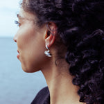 RA HA long sculptural earring in sterling silver, worn on ear