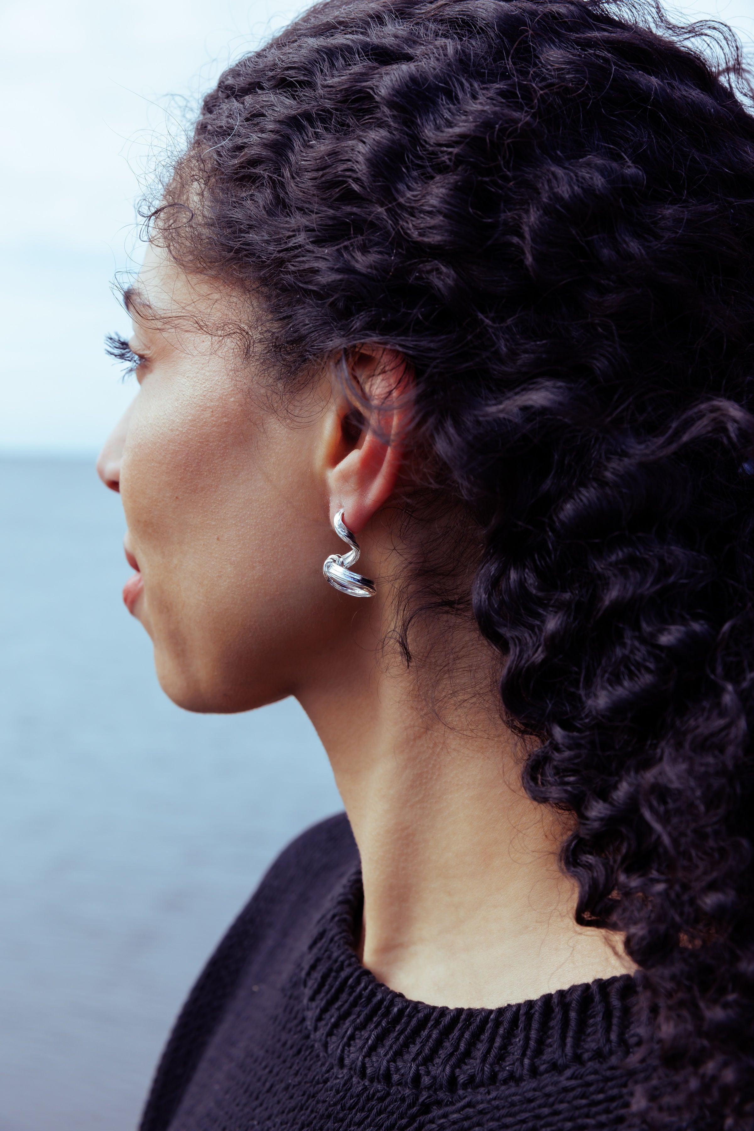RA HA long sculptural earring in sterling silver, worn on ear