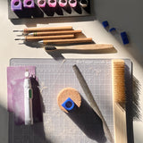 A set of wax carving tools, files, and ring models arranged on a work surface in a jewelry studio.